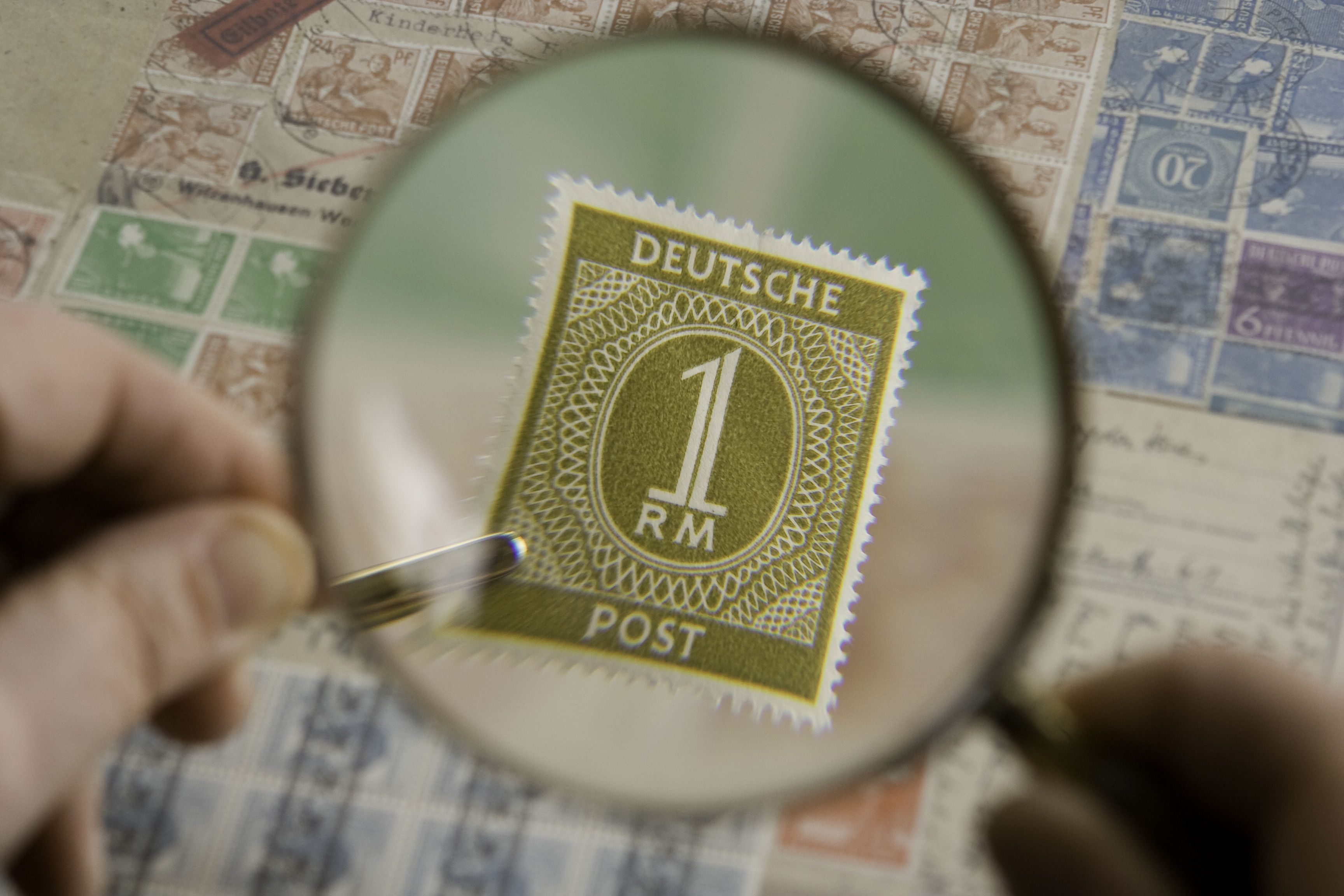 A magnifying glass inspecting a stamp collection